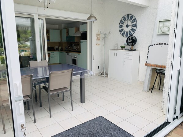 A modern kitchen with white cabinets, a dining table with chairs, and a large wall clock.