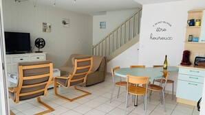 A modern living room with a sofa, chairs, a TV, and a dining table. - House for rent 200 meters from the beach, close to shops. (Saint-Jean-de-Monts)