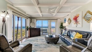 A spacious living room with a view of the ocean, leather sofas, a coffee table, and decorative mirrors. - Unbelievable Oceanfront Home, 6 bed/8 bath, 3036 S. Fletcher, Private Pool (Fernandina Beach)