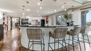 A modern kitchen with a central island, bar stools, and a view of the outdoors. - Unbelievable Oceanfront Home, 6 bed/8 bath, 3036 S. Fletcher, Private Pool (Fernandina Beach)