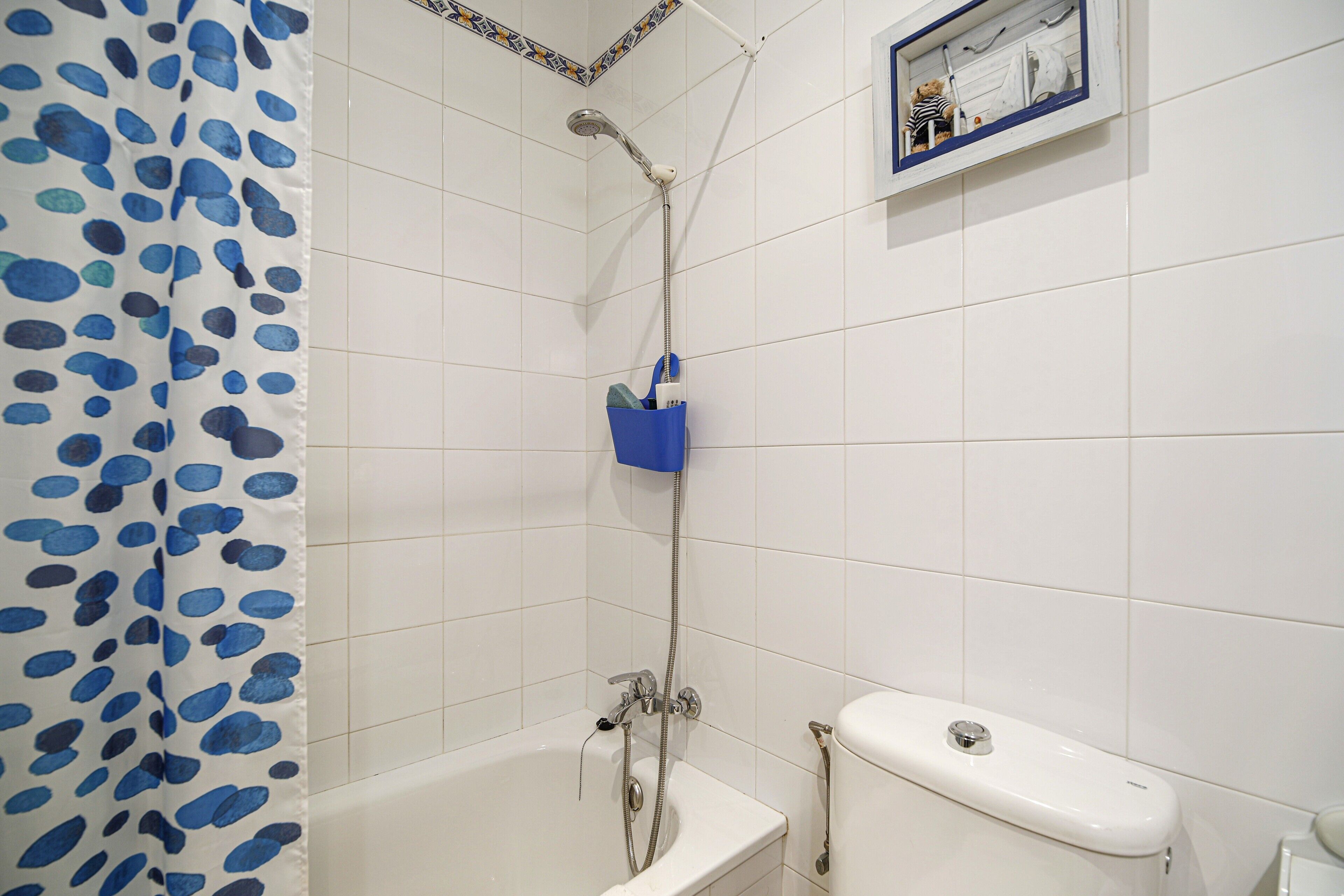 A bathroom with a shower, toilet, and a blue towel rack.