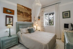 Une chambre à coucher avec un lit, des tables de chevet, une télévision et des œuvres d’art accrochées aux murs.