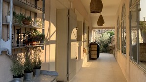 A corridor with potted plants, a hanging light fixture, and a view of the outside garden. - Luxury villa in town center; 5* in a quiet location  (Saint-Rémy-de-Provence)