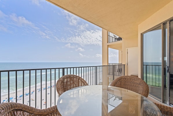Enjoy the ocean view from this balcony with wicker furniture and a glass table.