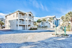 A beachfront property with a two-story building, a covered patio, and a sign indicating 'Turtle Beach'.