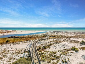 Une plage de sable avec une promenade en bois qui mène à l’eau.