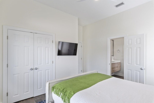 A bedroom with a bed, a television mounted on the wall, and a closet with a mirror.