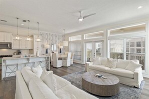 A modern living room with a sofa, a coffee table, and a dining area with chairs.