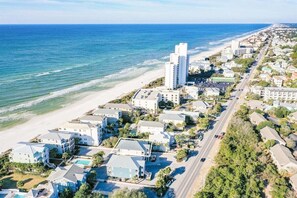A coastal residential area with beachfront properties, a main road, and a tall building.