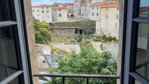 A view from a window overlooking a courtyard with buildings, a bridge, and greenery. - Mansion overlooking the ancient Roman arena (Béziers)
