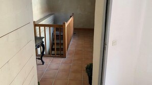 A narrow hallway with a wooden railing, a small table, and a potted plant. - Mansion overlooking the ancient Roman arena (Béziers)