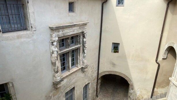 A narrow alleyway with a cobblestone path, a small archway, and a building with a window and a door. - Mansion overlooking the ancient Roman arena (Béziers)