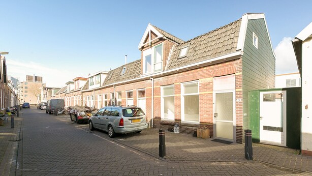A street with brick houses, a parked car, and a green door on the right. - Comfortable home near Amsterdam (Zaandam)