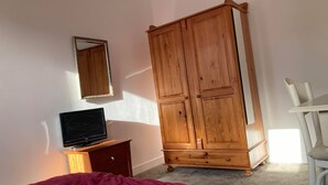 A bedroom with a bed, a wooden wardrobe, a television on a wooden stand, and a white chair. - Comfortable home near Amsterdam (Zaandam)