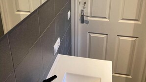 A bathroom with a white sink, dark tiled walls, and a white door with a handle. - Comfortable home near Amsterdam (Zaandam)
