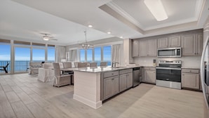 A modern kitchen with a large island, stainless steel appliances, and a view of the ocean. - New Complex!  Lazy River/Slide, Beachfront!  4BR, Sleeps 14! (Orange Beach)