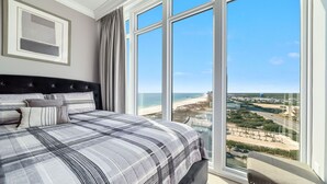 Una camera da letto con un letto grande, vista sulla spiaggia e sullo skyline della città.