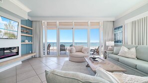 A spacious living room with a large sliding glass door leading to a balcony with a view of the ocean.