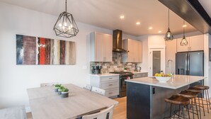 A modern kitchen with a central island, bar stools, and pendant lighting. - 845 Mill Run Court 5 Bedroom Home by RedAwning (Steamboat Springs)
