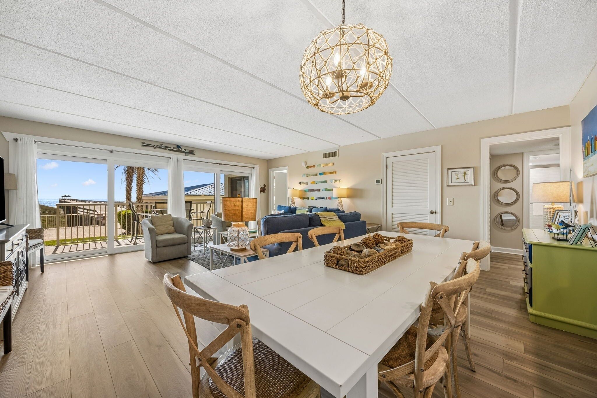 A spacious living area with a dining table, chairs, a sofa, and a chandelier.