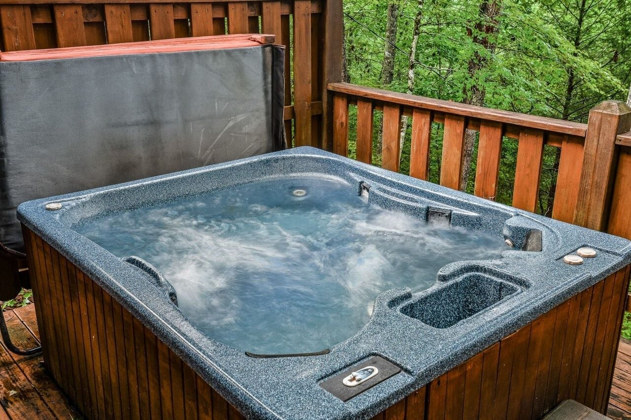 A hot tub on a wooden deck with a view of a forest.