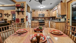 Una cocina acogedora con armarios de madera, una mesa de comedor preparada con platos y cubiertos, y un pequeño coche de juguete como adorno central.