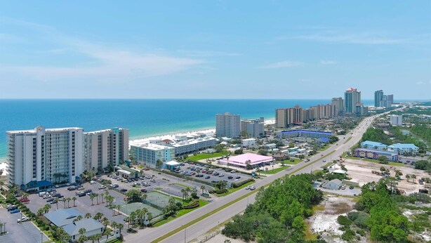 Un paysage urbain côtier avec de hauts immeubles, une plage et un parking.