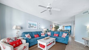 A living room with a blue sofa set, a white coffee table, and a ceiling fan. - Windward Pointe 502-Beachfront 3bd/2ba-Sleeps 8-Heart of Orange Beach (Orange Beach)