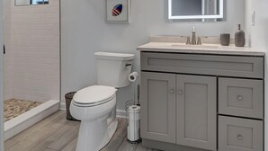 A modern bathroom with a toilet, vanity, and a shower area.