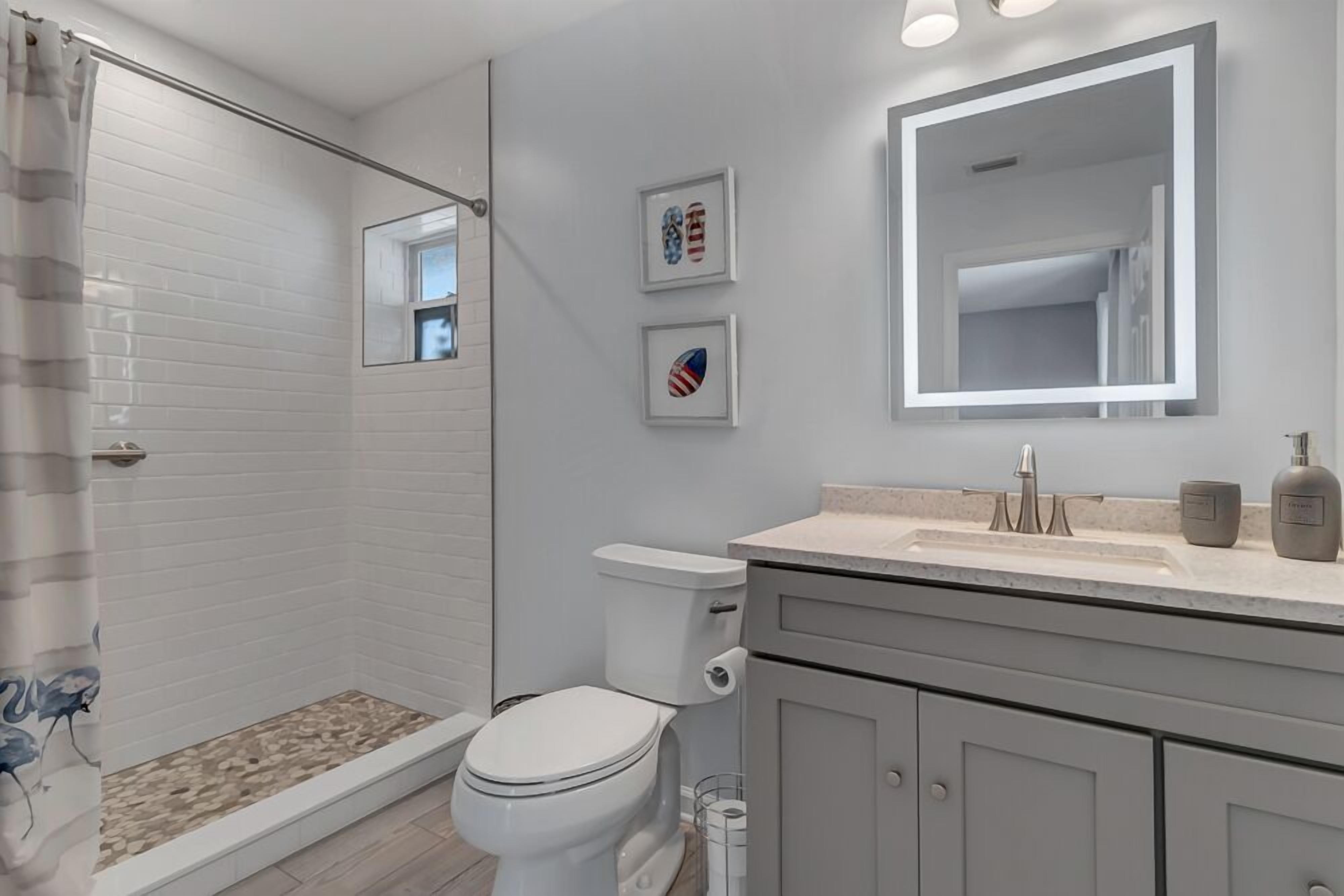 A modern bathroom with a shower, toilet, and vanity.
