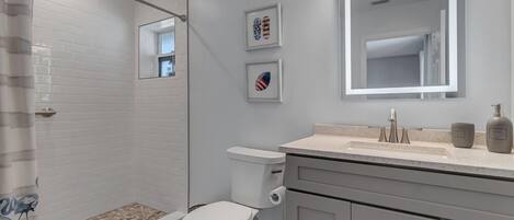 A modern bathroom with a shower, toilet, and vanity.