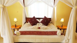 Una cama con dosel, dos mesitas de noche con lámparas y almohadas decorativas.