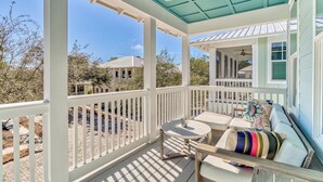 A covered porch with a white railing, a ceiling fan, and a view of neighboring houses.