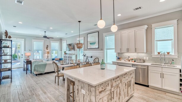 A spacious kitchen with a large island, white cabinetry, and pendant lighting.