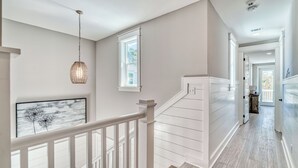 A staircase with white railings and a hanging light fixture.