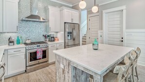 A modern kitchen with white cabinetry, stainless steel appliances, and a marble island.