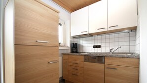 Eine Küche mit Holzschränken, einem Geschirrspüler und einer Kaffeemaschine.