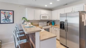 A modern kitchen with white cabinets, a stainless steel refrigerator, a microwave, and a sink. - Relax by the River | Shared Pool | Labor Day Ready (New Braunfels)