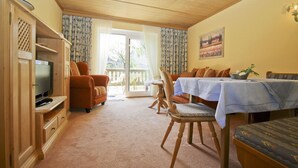 A cozy living room with a television, a dining table with chairs, and a sofa. - Apartment 2, 55sqm, terrace, kitchen extra, 1 bedroom, max 2 pers., WLAN (Ruhpolding)