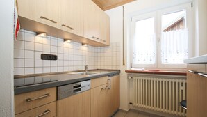 A modern kitchen with wooden cabinets, a built-in dishwasher, and a window with a view of the outside. - Apartment 2, 55sqm, terrace, kitchen extra, 1 bedroom, max 2 pers., WLAN (Ruhpolding)