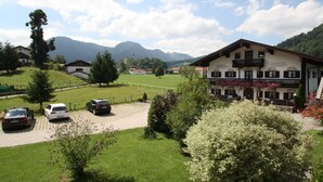 A building with a balcony and flower boxes, surrounded by greenery and parked cars. - Apartment 2, 55sqm, terrace, kitchen extra, 1 bedroom, max 2 pers., WLAN (Ruhpolding)
