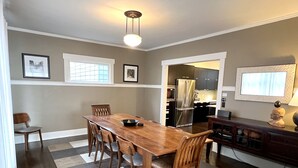 Un comedor con una mesa y sillas de madera, una cocina con electrodomésticos modernos y un tapete estampado.