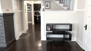 Un interior moderno con piso de madera oscura, paredes blancas y una escalera que sube a un nivel superior.
