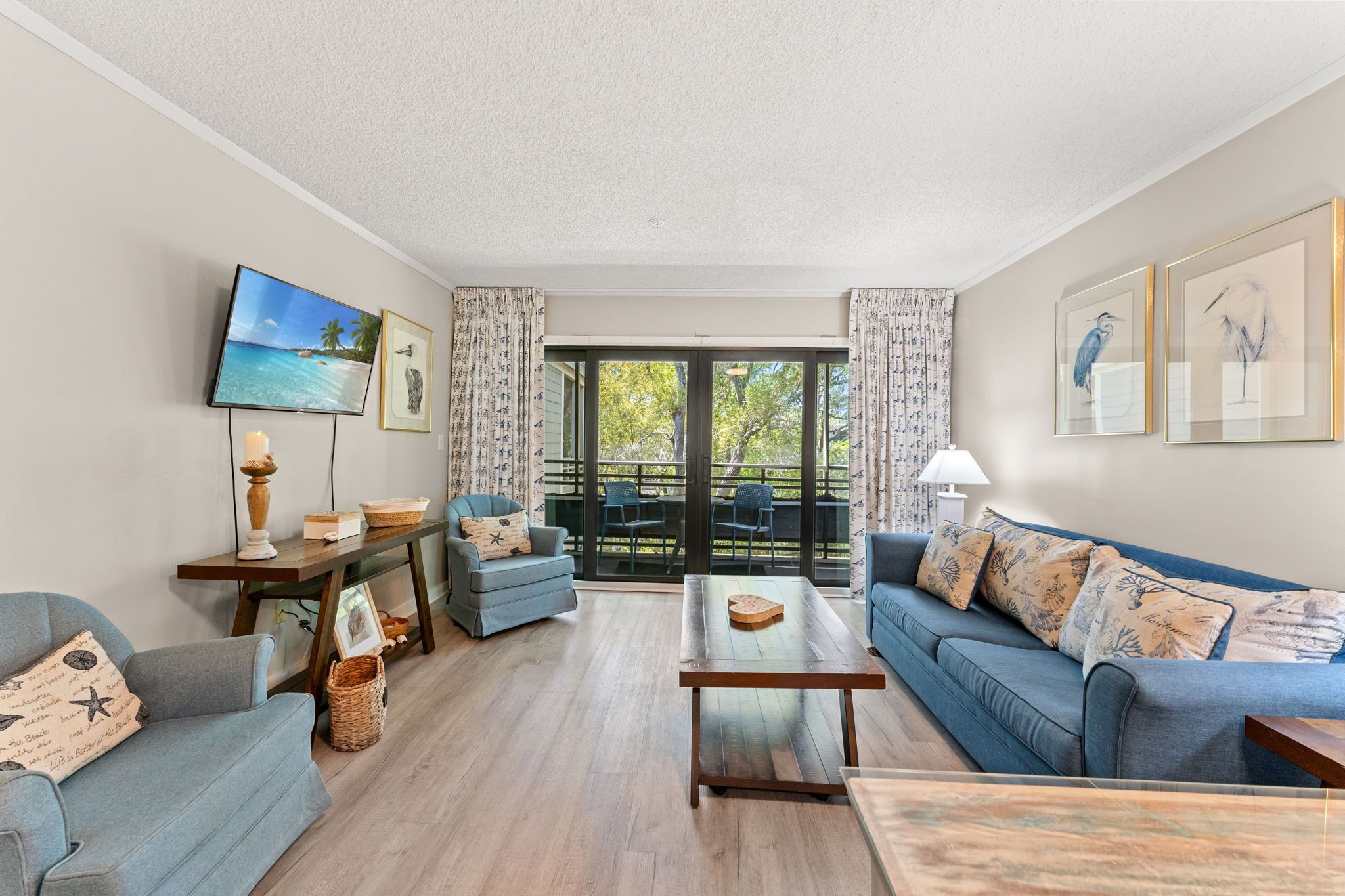 Un salon comprenant un canapé, une table basse, un téléviseur et un balcon aménagé avec du mobilier d’extérieur.