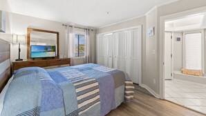 Une chambre à coucher comprenant un lit, une télévision, une commode, un miroir et une fenêtre avec des stores.