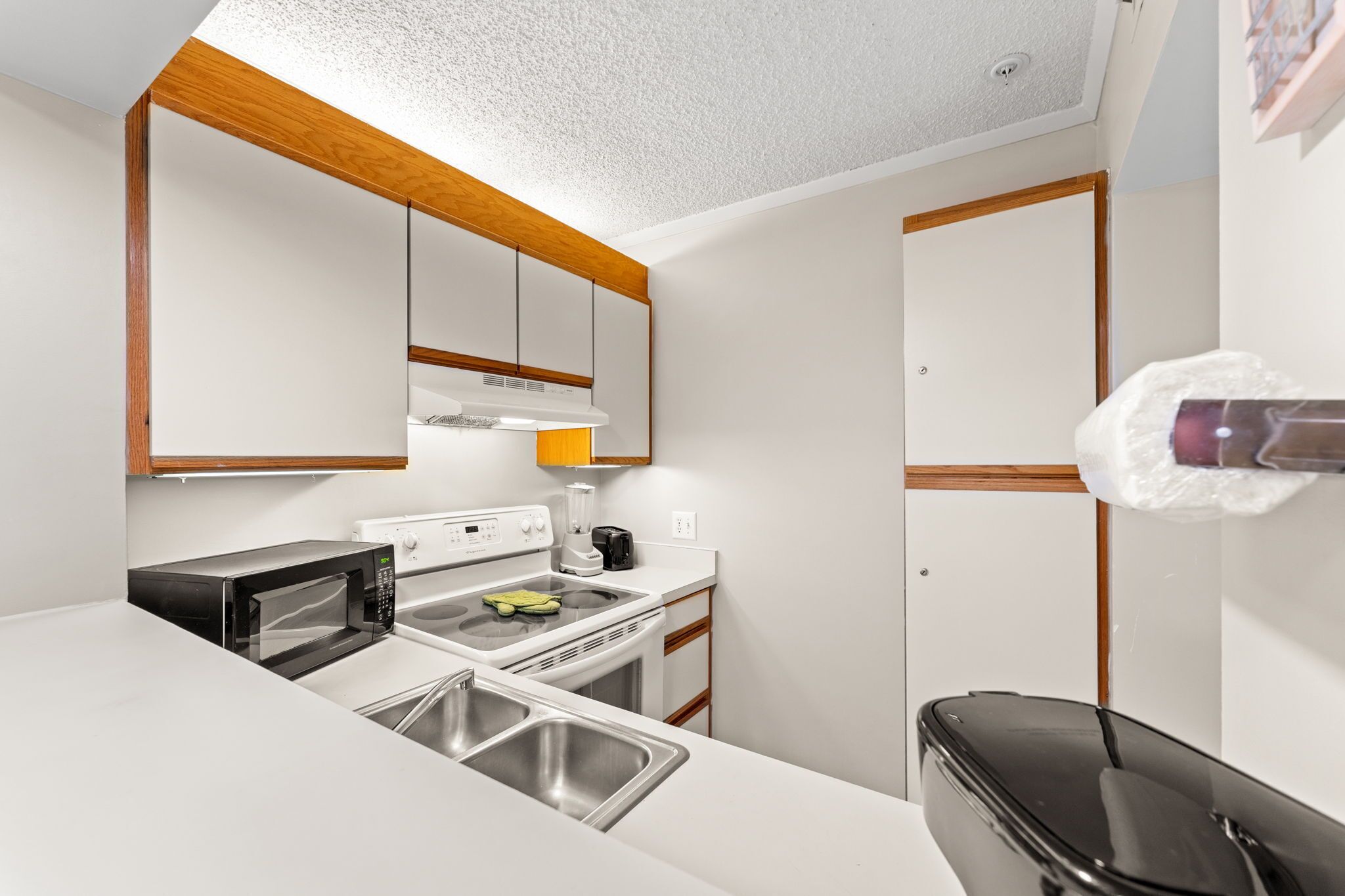 A compact kitchen with a microwave, stove, sink, and a small refrigerator.