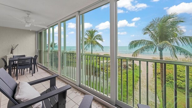 A balcony with a view of the beach and palm trees.