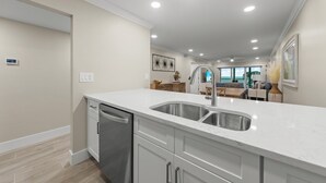 A modern kitchen with a double sink, stainless steel appliances, and a clean, white countertop.