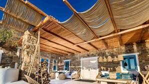 A traditional stone building with a wooden ceiling and woven fabric awnings. - Karkos Beachfront Villa  Private pool (Mykonos)