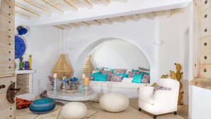 A cozy living room with a white sofa, round poufs, and a coffee table with decorative items. - Karkos Beachfront Villa  Private pool (Mykonos)